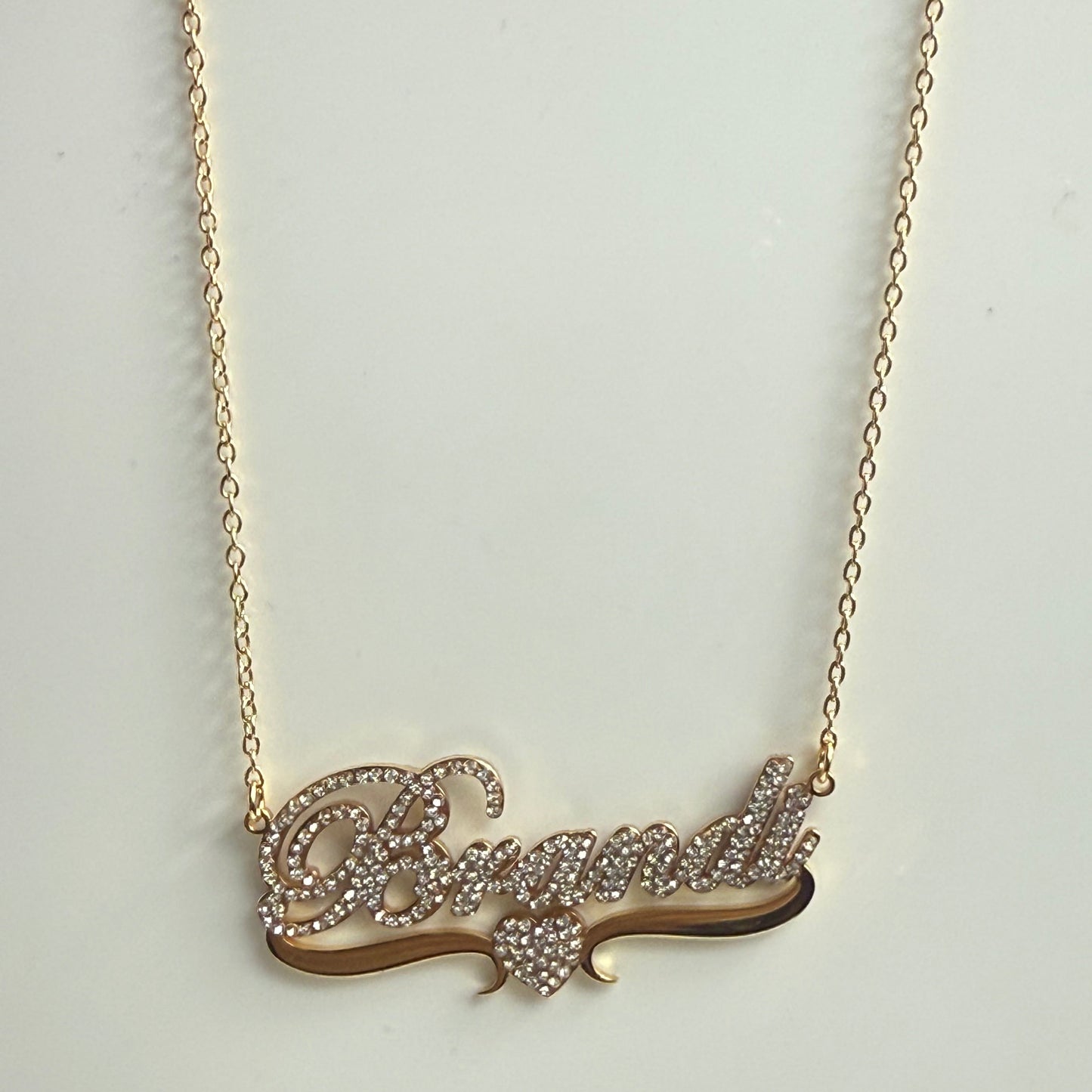 Gold necklace with a decorative pendant on a light gray background