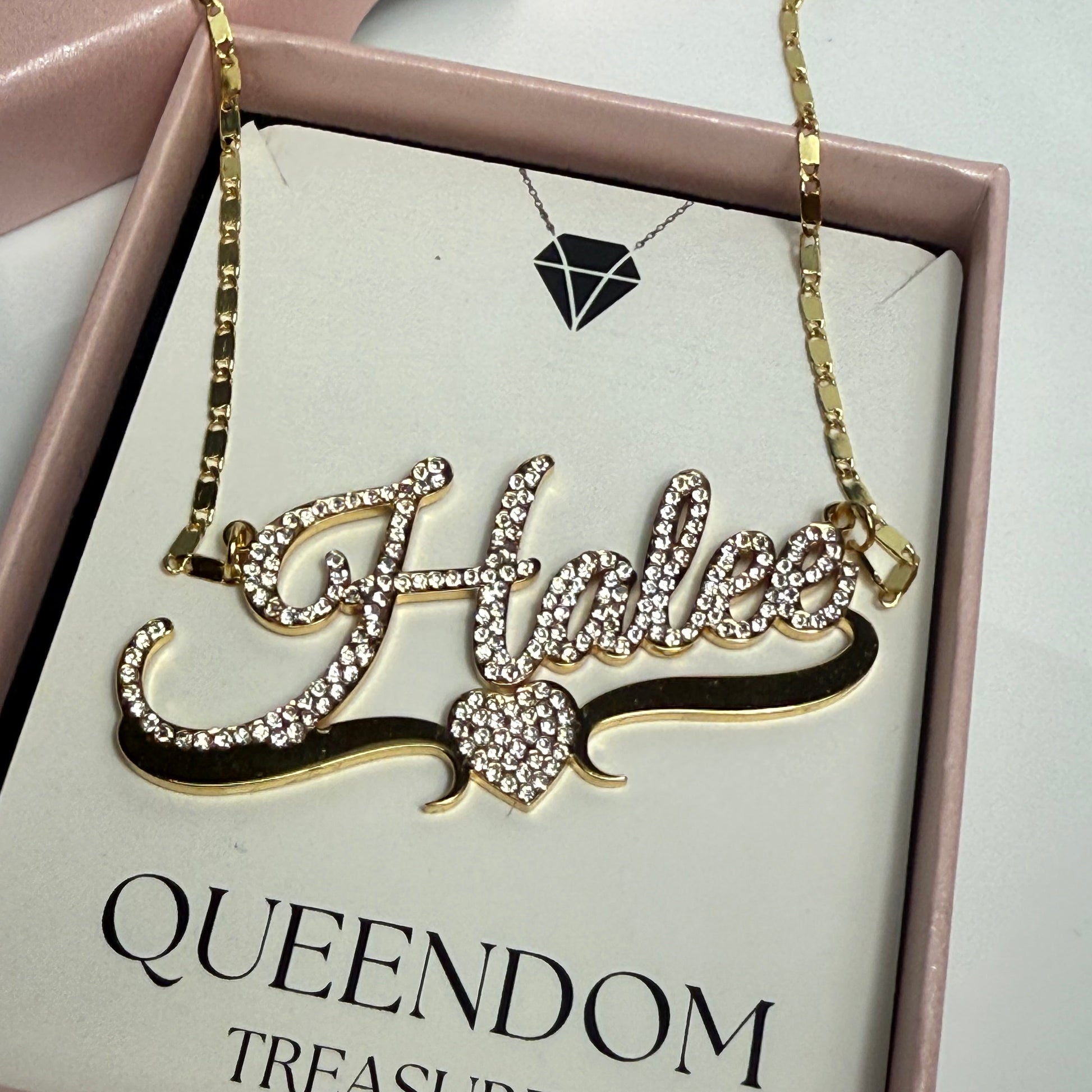 Decorative necklace with rhinestones on a 'QUEENDOM TREASUREZ' branded card.