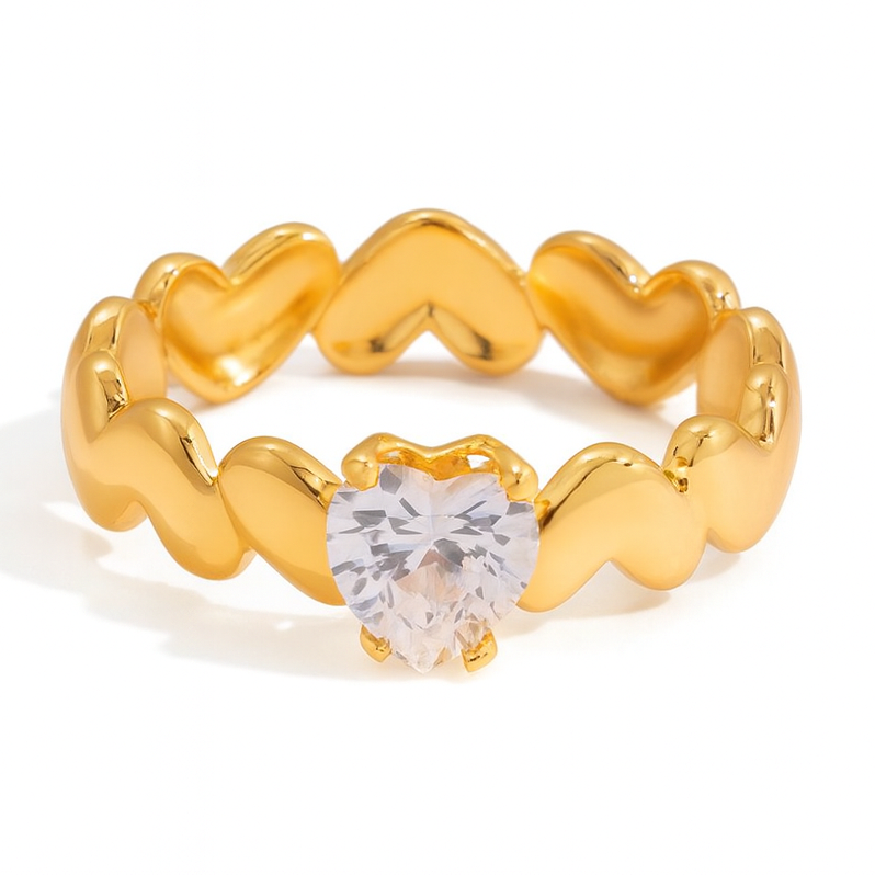 Gold ring with heart-shaped design and clear gemstone on a white background