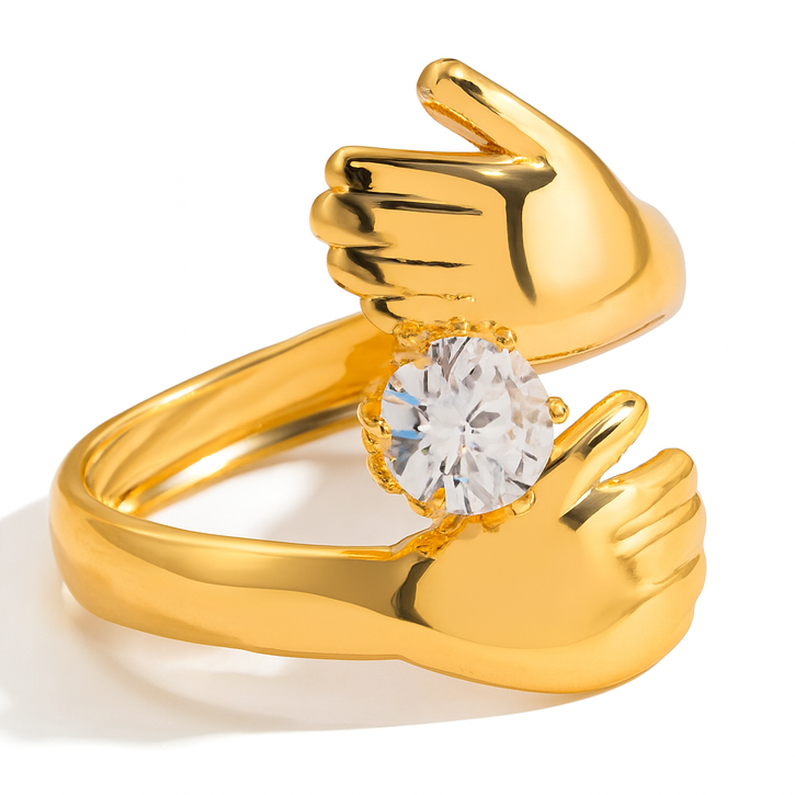 Gold ring with a diamond set in a design resembling clasped hands on a white background