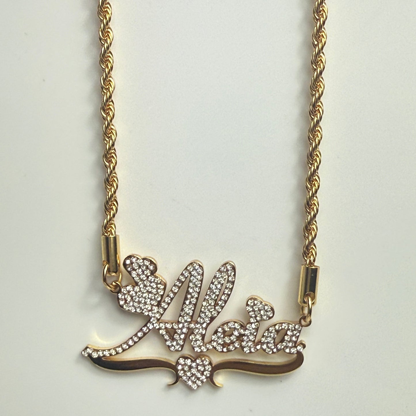 Gold necklace with a decorative bow pendant on a light gray background