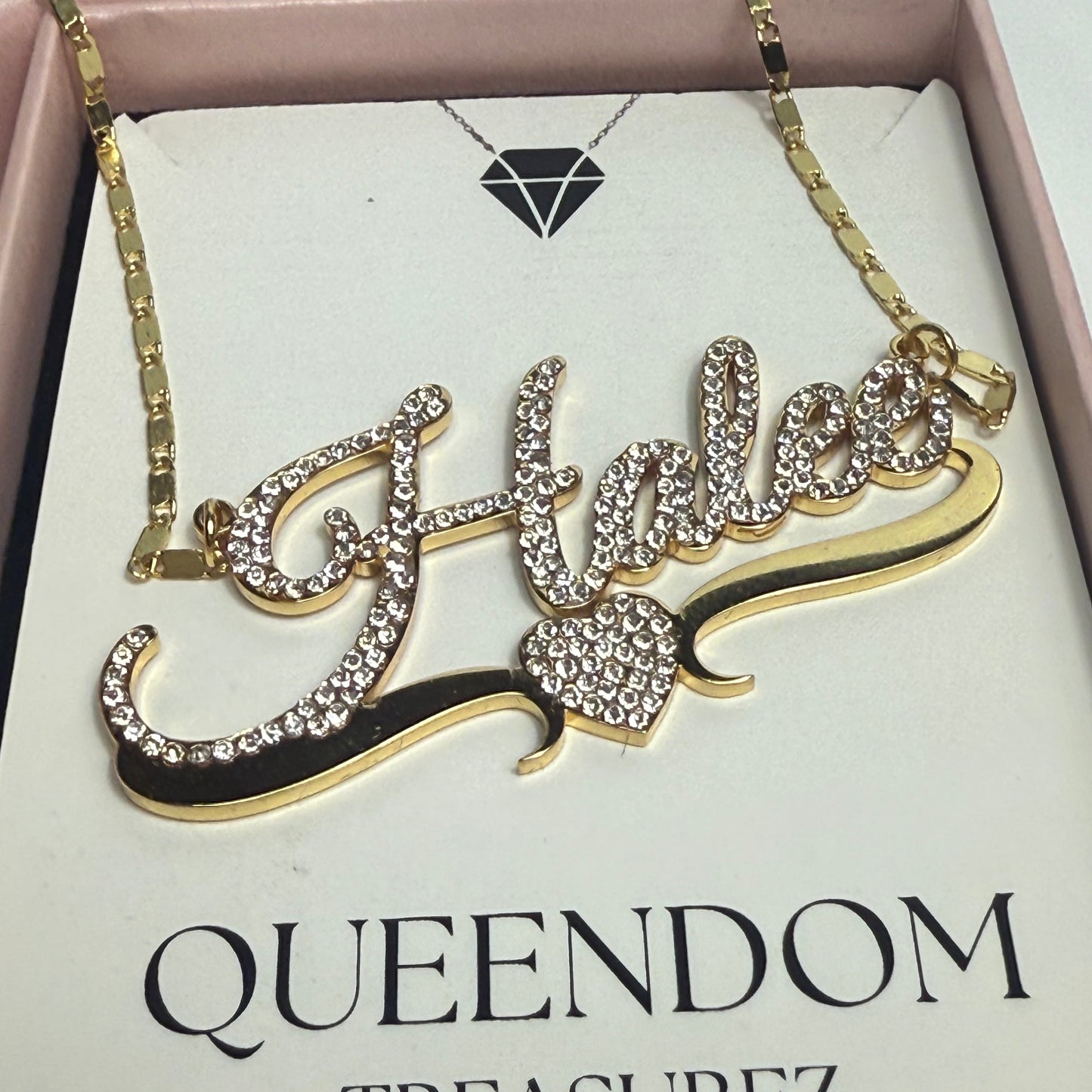 Decorative brooch with 'QUEENDOM TREASUREZ' branding on a box.
