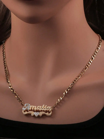 A gold chain necklace with a personalized nameplate pendant spelling 'malia' in gold script, accented with small clear rhinestones and a small heart, shown on a mannequin bust.