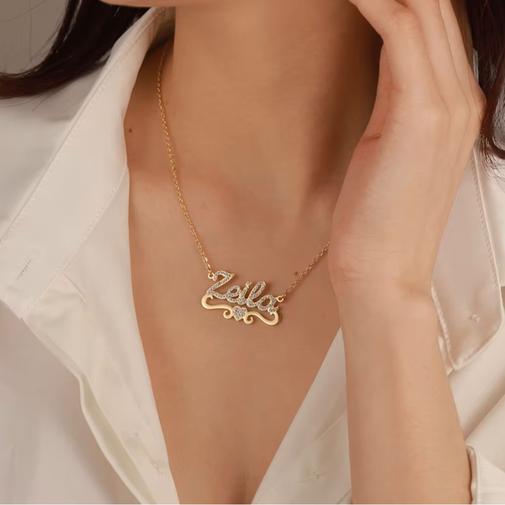 Woman wearing a gold necklace with 'Zella' pendant against a neutral background