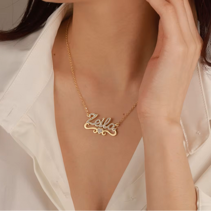 Woman wearing a gold necklace with 'Zella' pendant against a neutral background